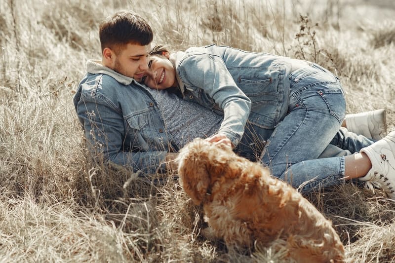 lyckliga par med hunden som ligger på gräset