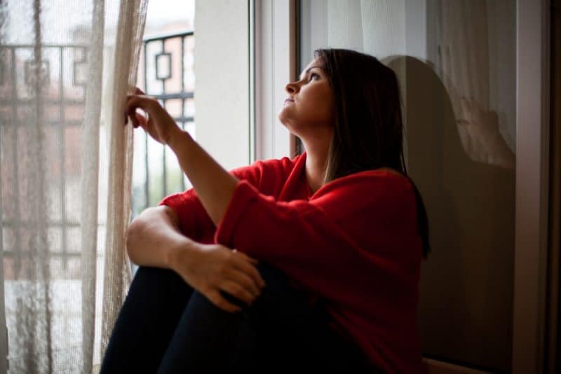 ensam ledsen kvinna som sitter vid fönstret