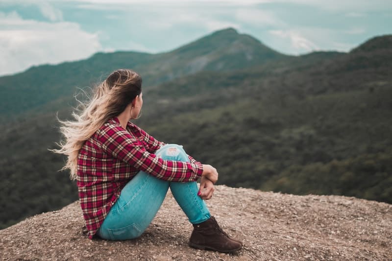 kvinna i jeans som sitter på kullen