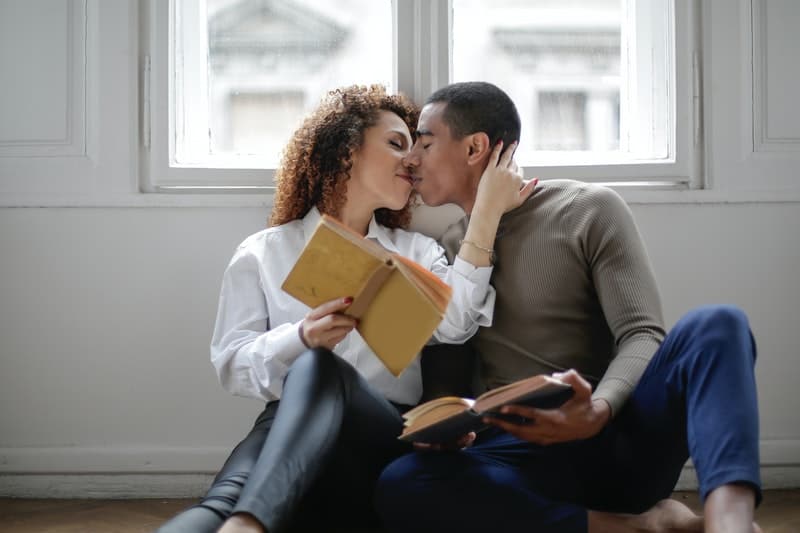 man och kvinna läser bok och kysser