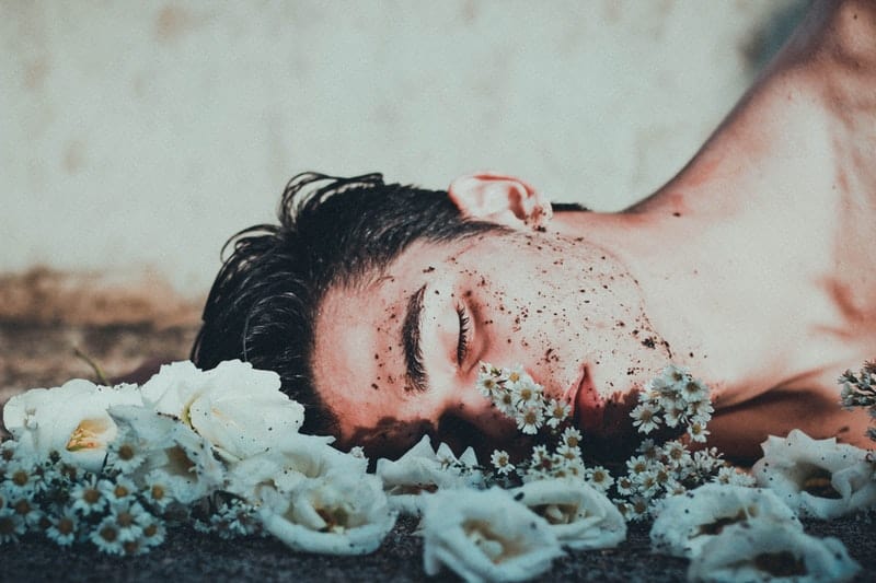 man som ligger på vita blommor