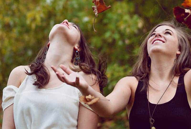 två unga kvinnor som ler utomhus
