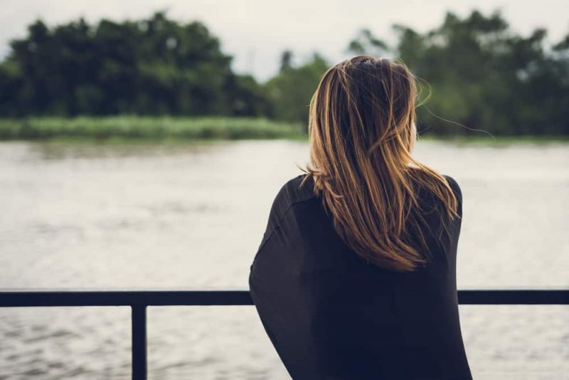 Ensam kvinna som sitter och ser floden