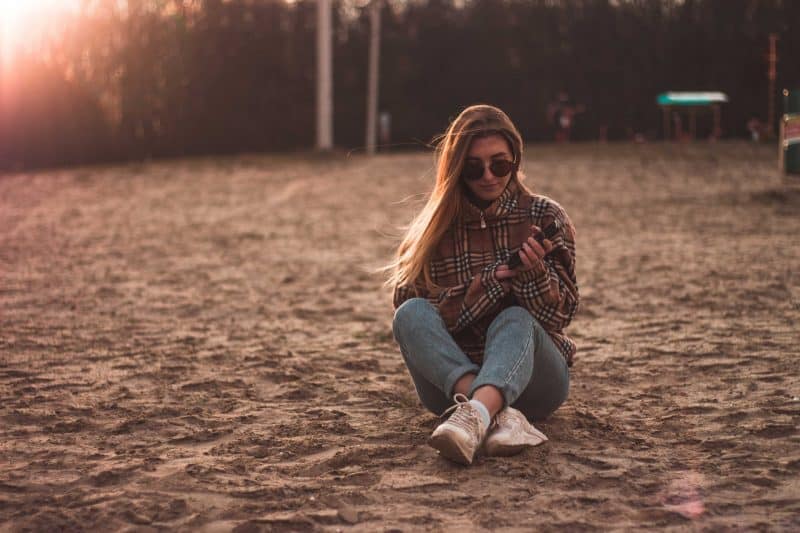 kvinna som håller en telefon som står ensam på stranden