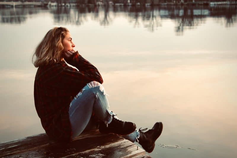 kvinna som sitter ensam vid sjön
