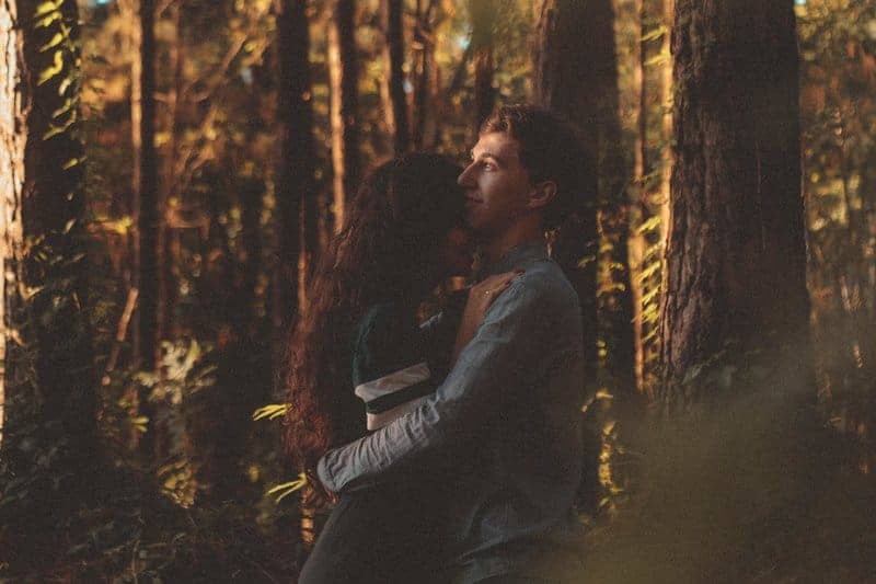 man och kvinna som kramar i skogen