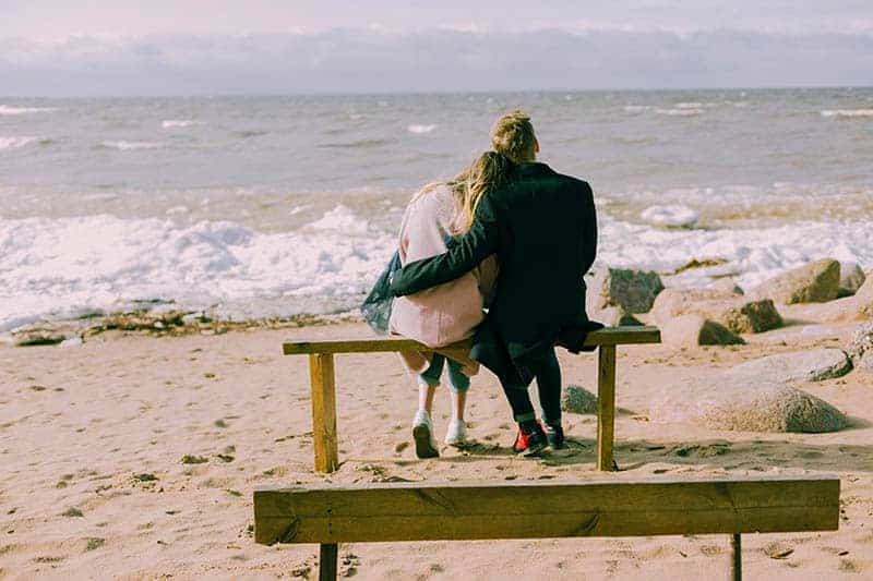 par sitter och kramar på stranden
