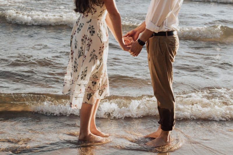 par som håller händerna på stranden