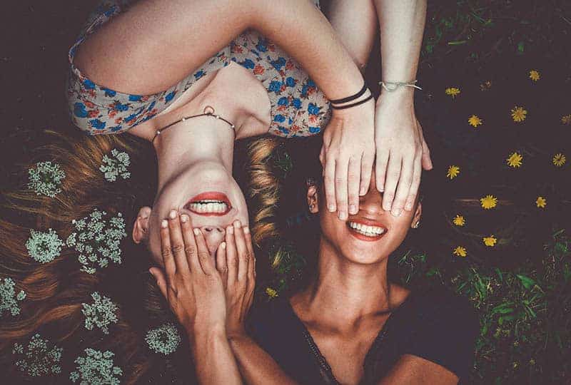två kvinnor som ler med blommor i hår