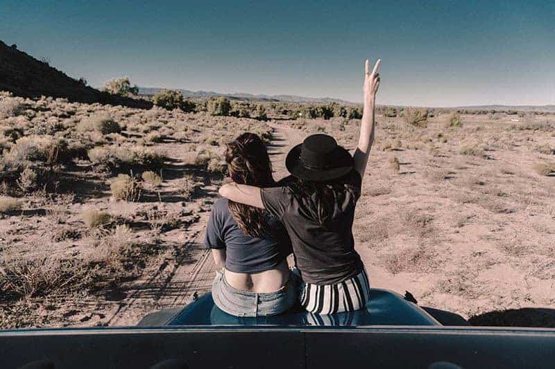 två kvinnor sitter på en bil och kramar