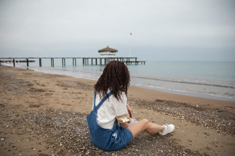 kvinna med lockigt hår som sitter på stranden