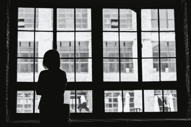 ensam kvinna som tittar genom fönstret