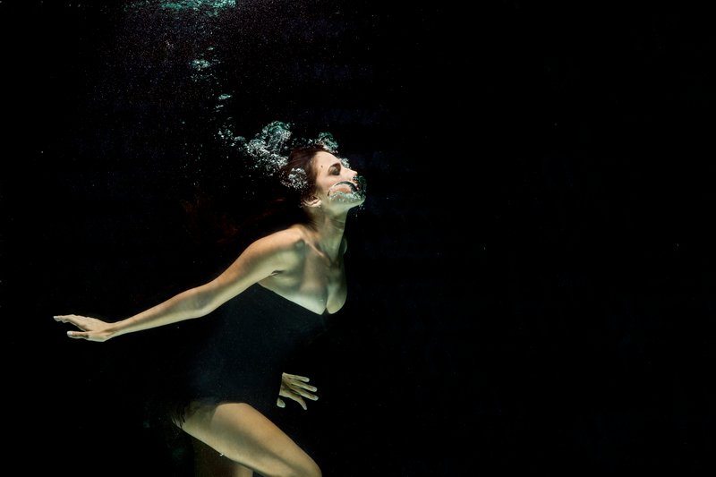 kvinna som bär svart klänning under vatten