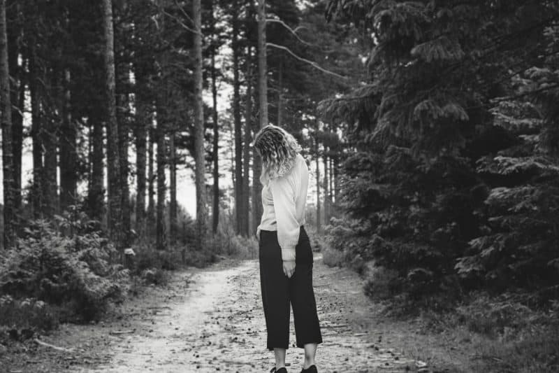 kvinna som står ensam i skogen