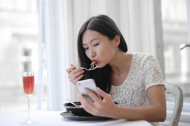 asiatisk ung kvinna äter nudlar på ett café