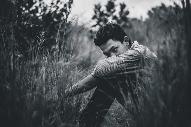 ensam man som sitter i högt gräs