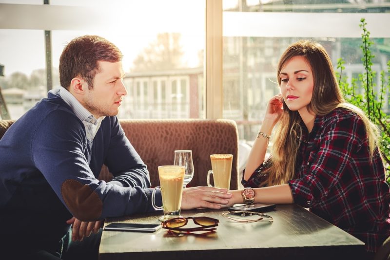 Ledsna romantiska par som rymmer händer på kaféet