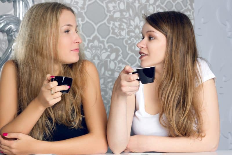 två unga kvinnor som dricker kaffe