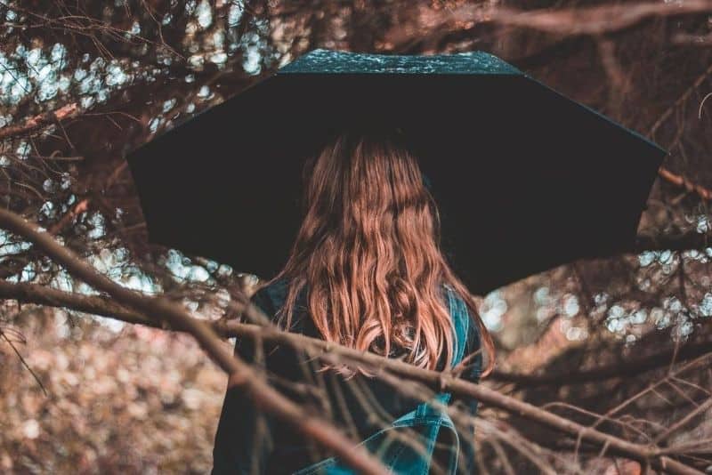 brunhårig kvinna med grönt paraply i naturen