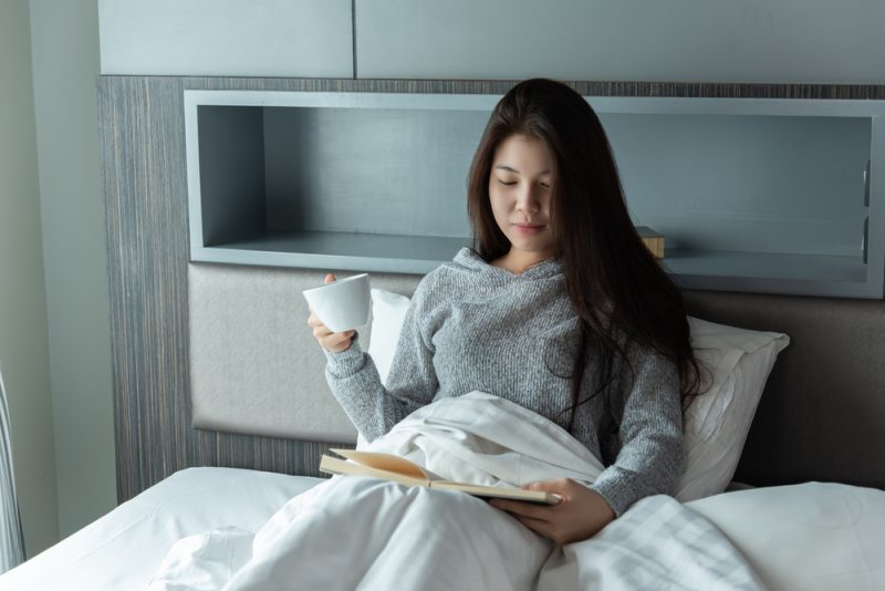kvinna läser bok i sängen