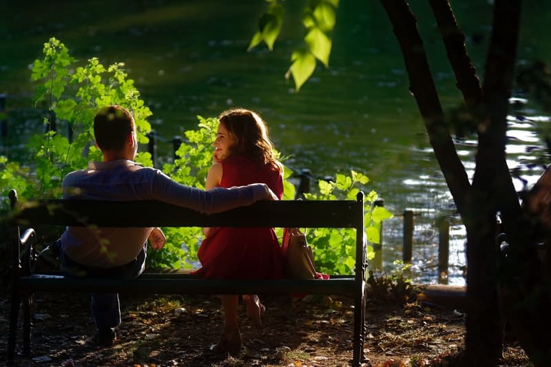 par som sitter på bänken och tittar på sjön
