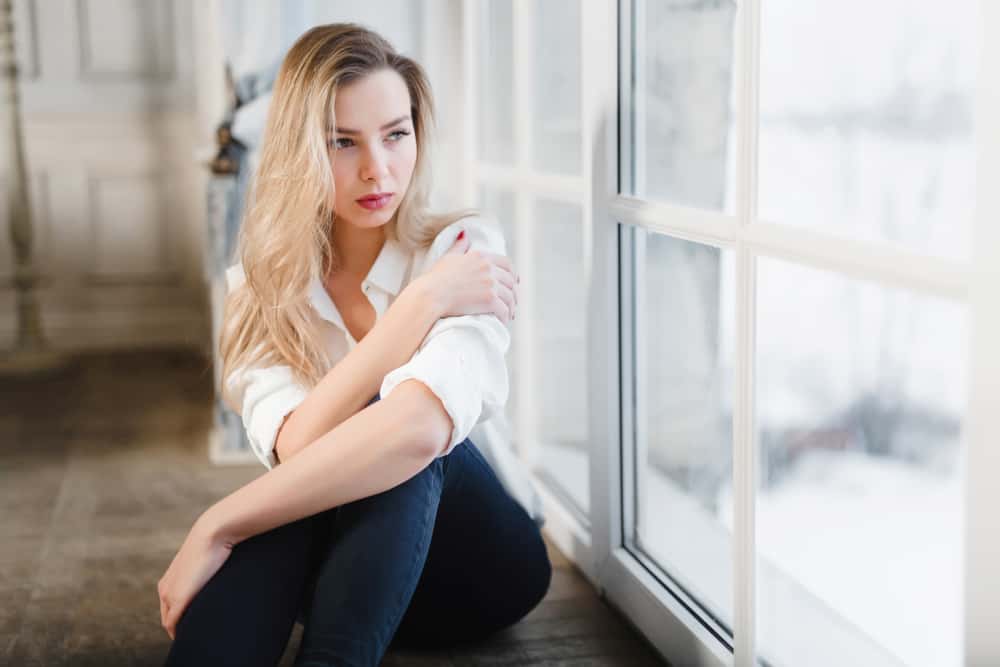 blond kvinna sitter och tittar genom fönstret
