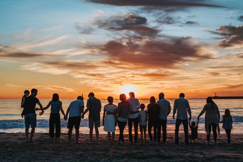 en stor familj på stranden och tittar på solnedgången