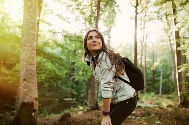 glad kvinna vandring i skogen