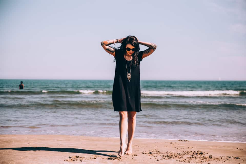 kvinna i svart klänning på stranden