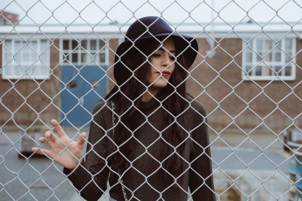 kvinna med hatt bakom staketet