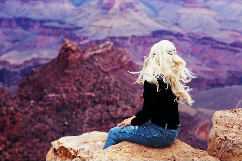 blond kvinna sitter på en klippa