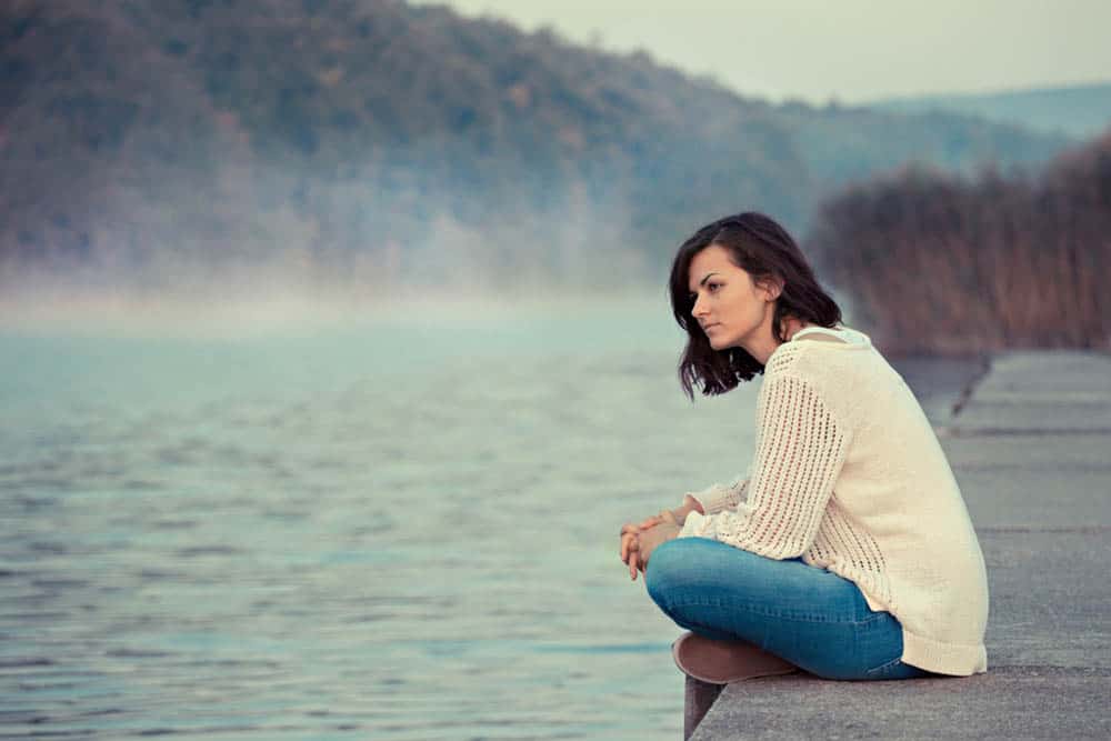 kvinna sitter vid sjön