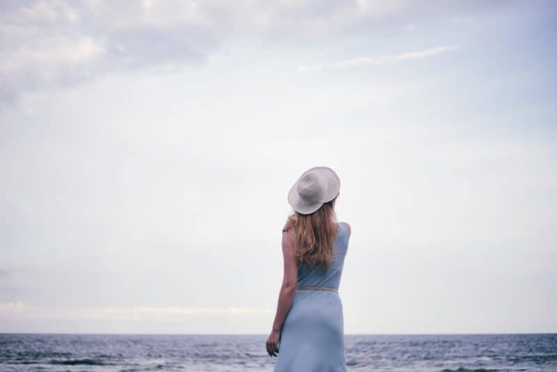kvinna som bär hatt som står på stranden