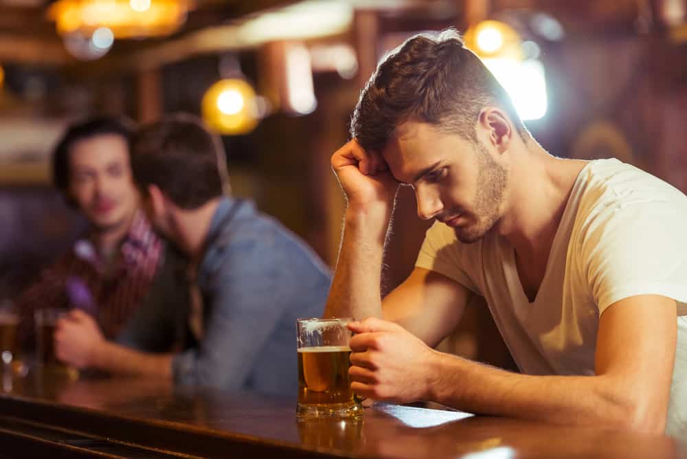 ledsen man som dricker öl i baren