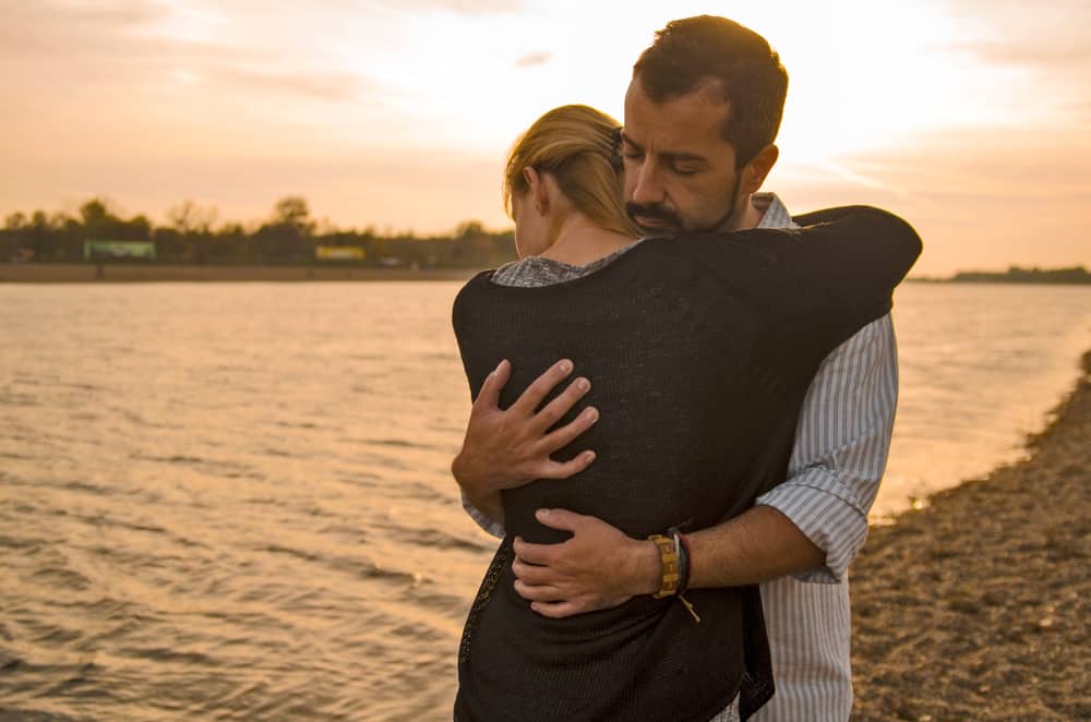 man och kvinna som kramar vid sjön