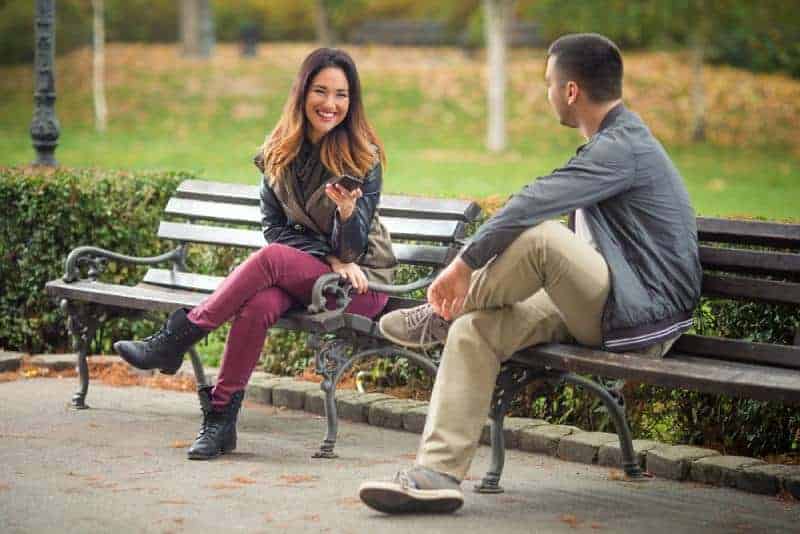 par som sitter på en bänk i en park och pratar