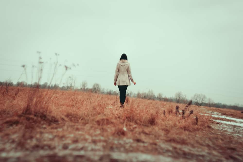 Ung kvinna som går på gräsfältet ensam