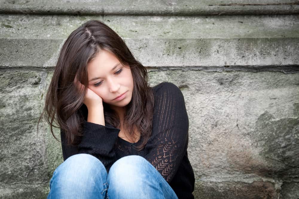 Utomhus porträtt av en sorglig tonårsflicka som ser fundersam om problem