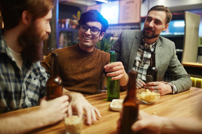 en grupp vänner i en bar som pratar och dricker öl