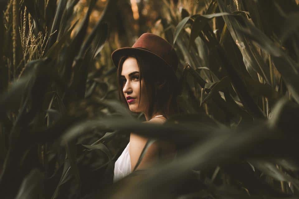 kvinna med brun hatt som står i sädesfält