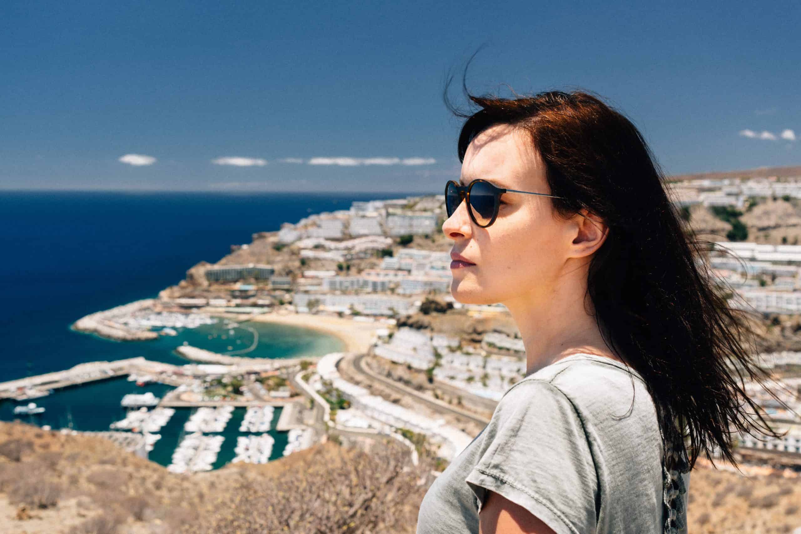 kvinna med solglasögon tittar på staden från kullen