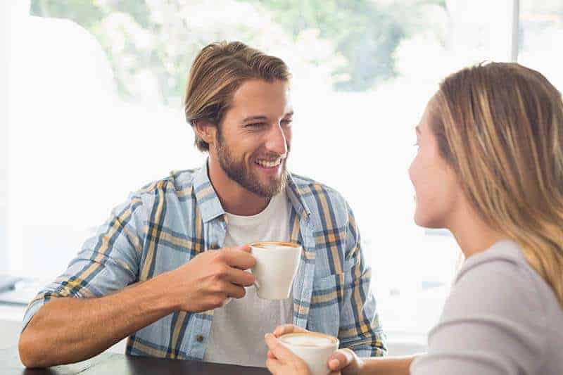 lyckliga par pratar medan man dricker kaffe
