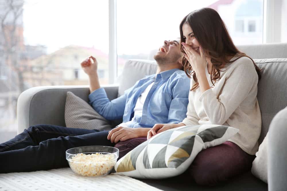 lyckliga paret som tittar på filmer hemma