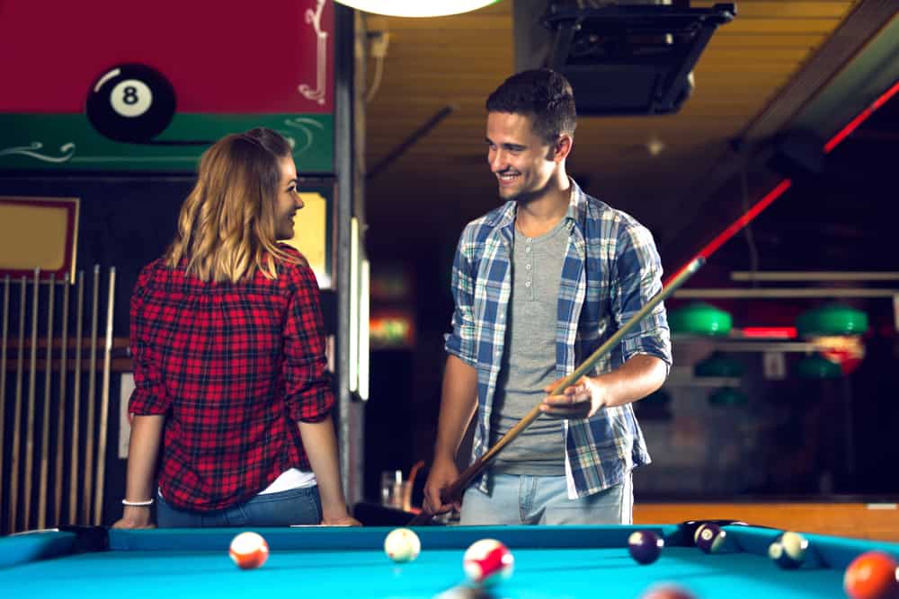 man och kvinna flörtar medan du spelar pool