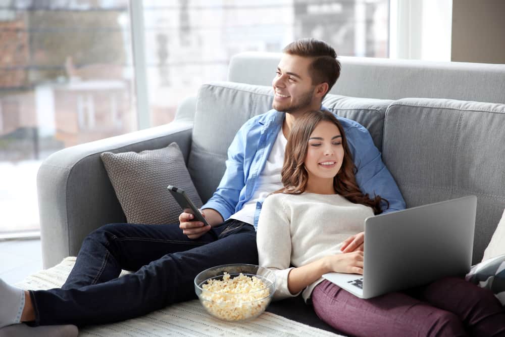 man tittar på tv och kvinna tittar på laptop