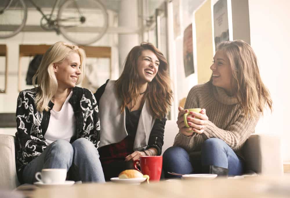 tre kvinnor som sitter på café och har roligt