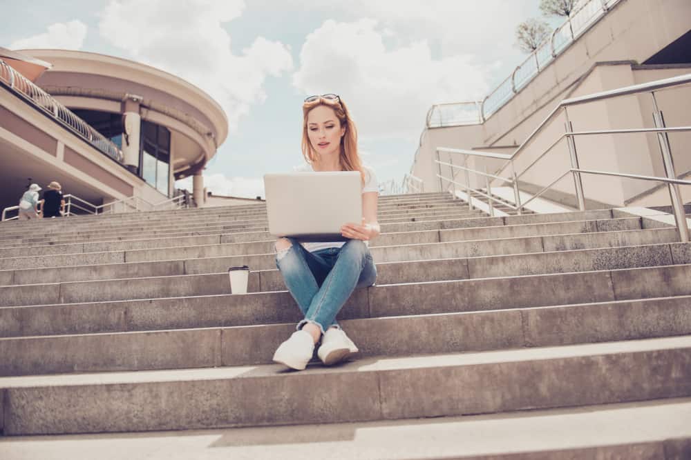 ung kvinna sitter på trappan med laptop