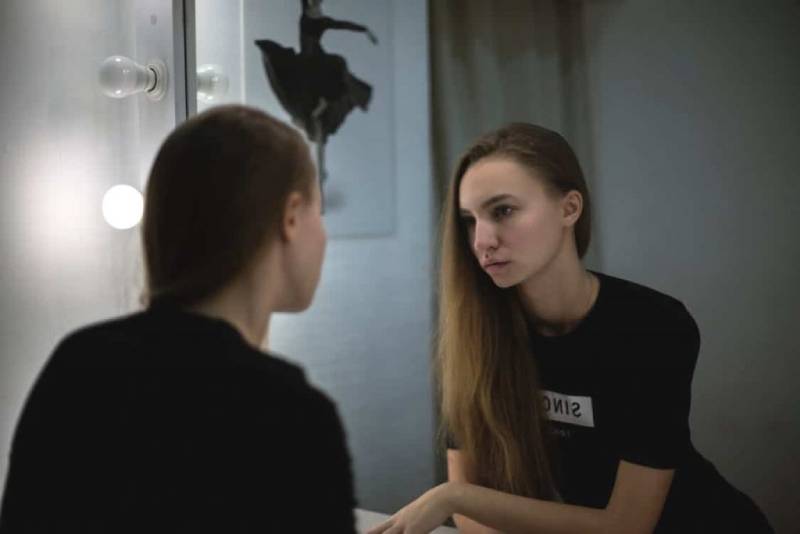 ung kvinna som ser sig själv i spegeln