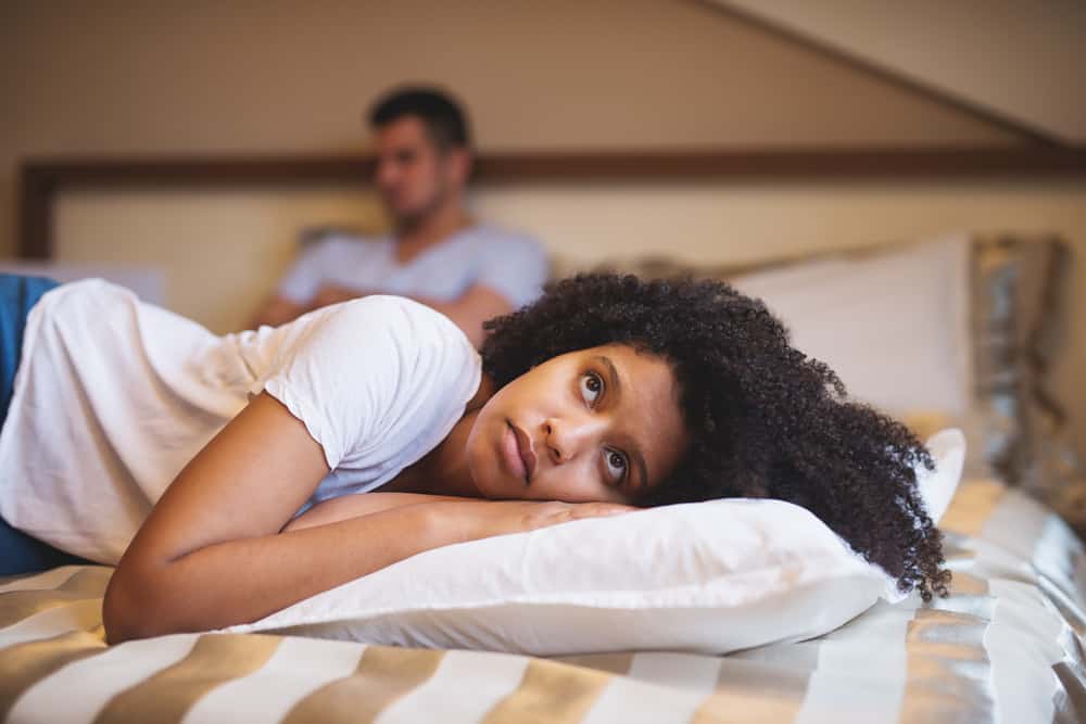 Ledsen kvinna som ligger på sängen efter ett argument med sin pojkvän