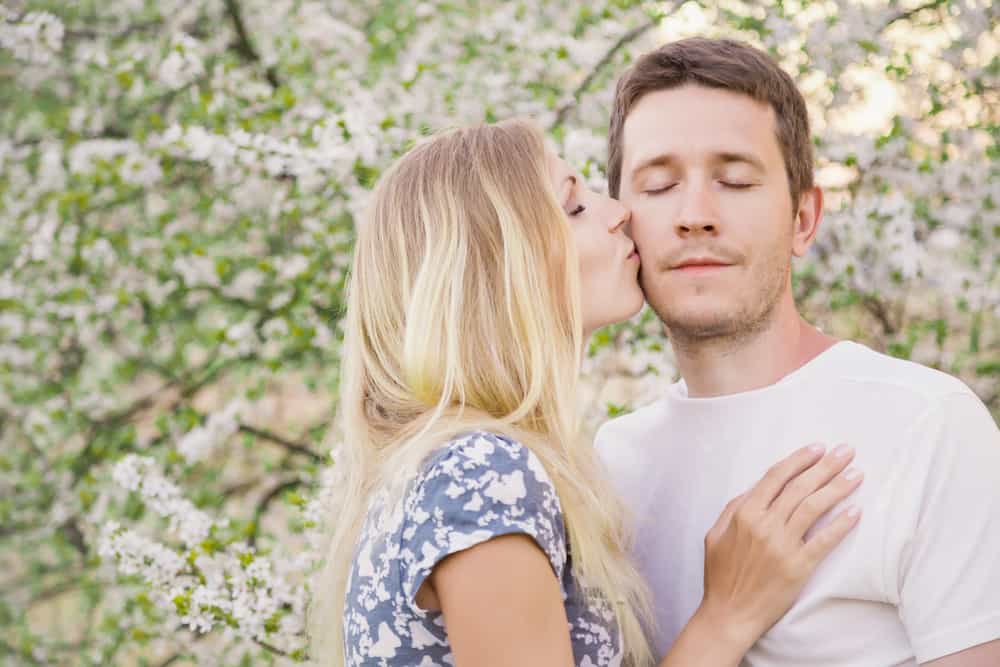 Ung kvinna som kysser en man på kinden
